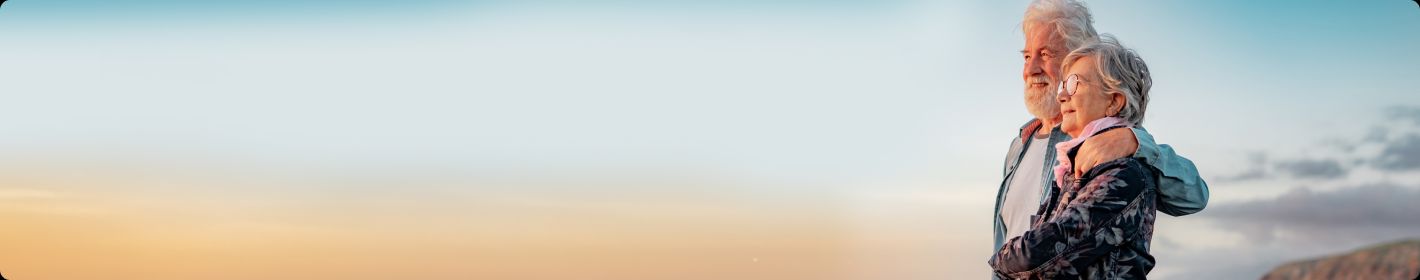 Couple standing together beside a sunset coastline.